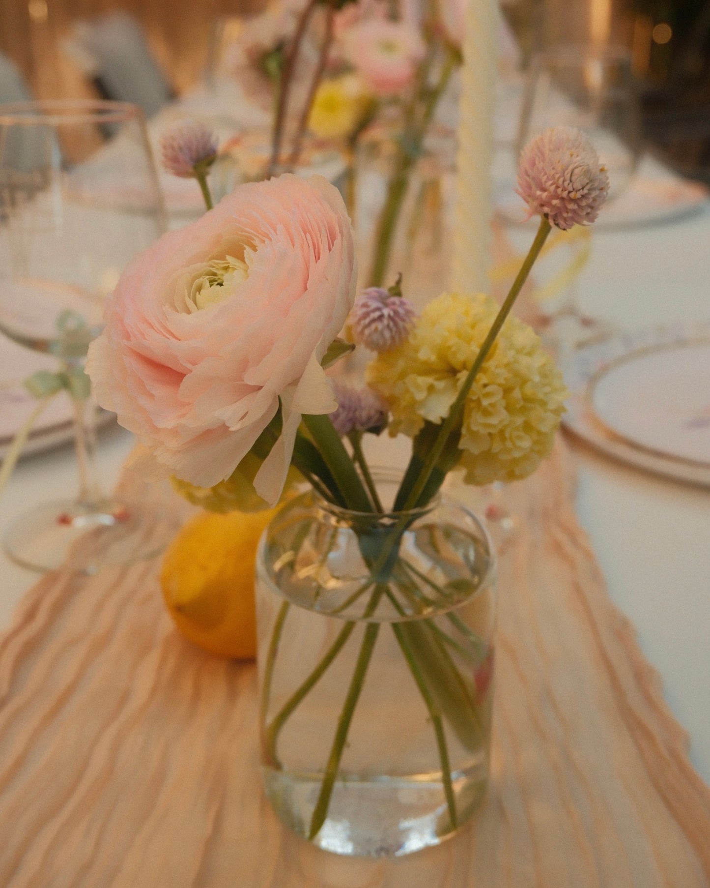 Vase with pink and yellow flowers on a table setting