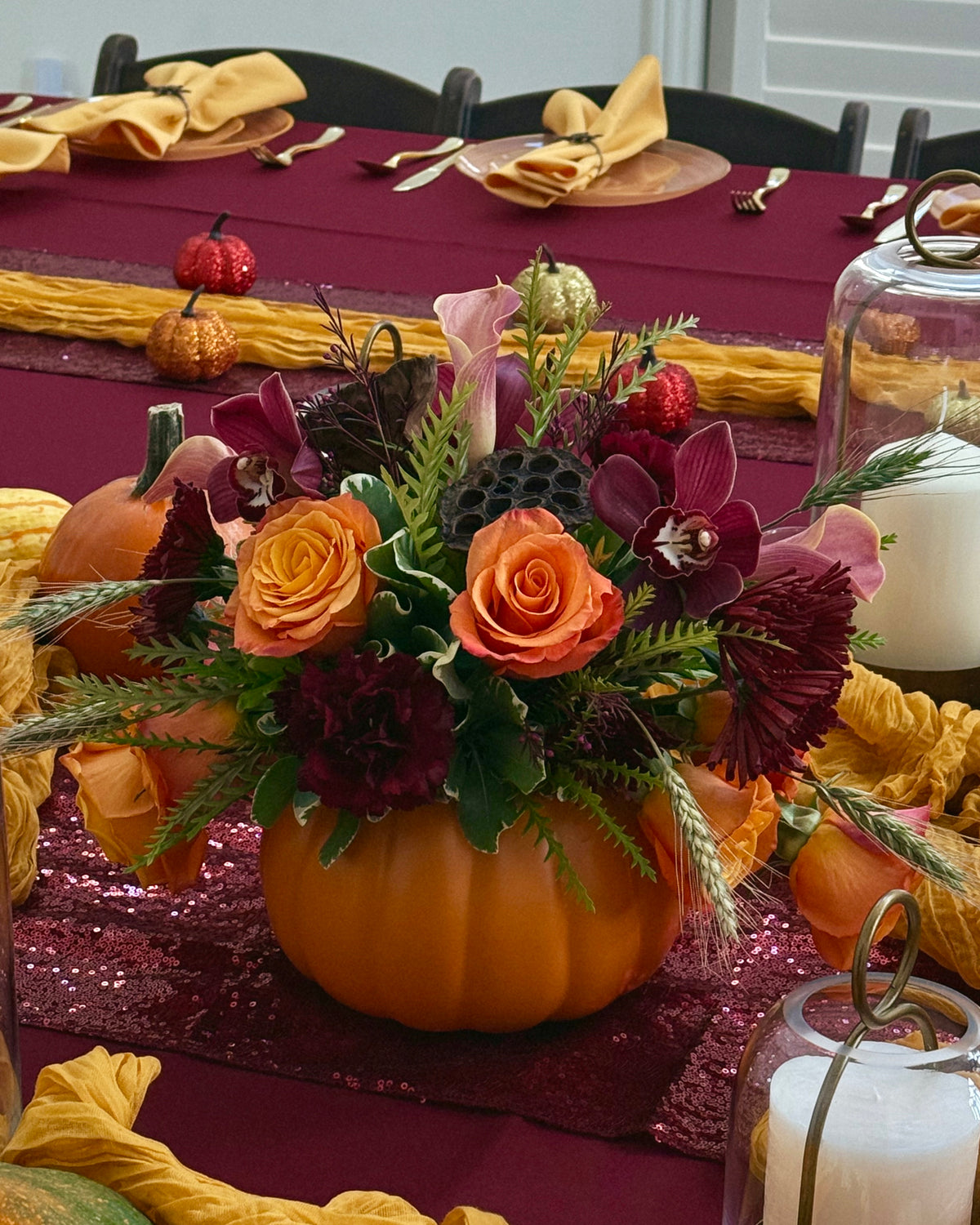 Decorative pumpkin with flowers on a table set for a meal.