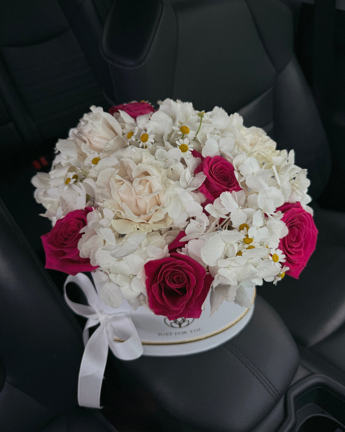 Bouquet of white and pink flowers in a box on a car seat
