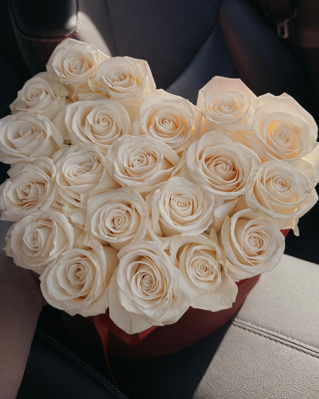 Bouquet of white roses held by a person in a car.