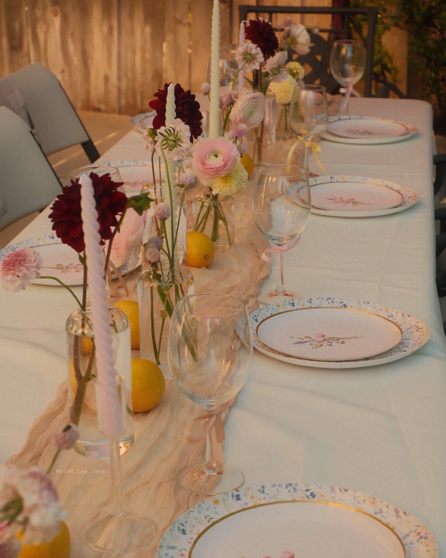 Elegant table setting with floral arrangements, candles, and decorative plates.