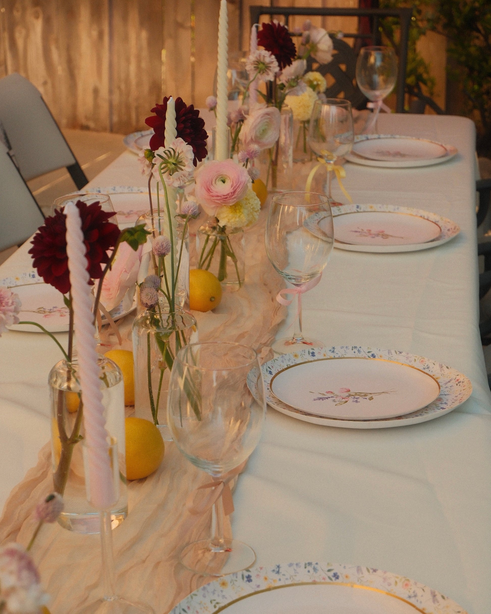 Elegant table setting with floral arrangements, candles, and decorative plates.