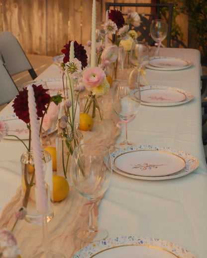 Elegant table setting with floral arrangements, candles, and decorative plates.