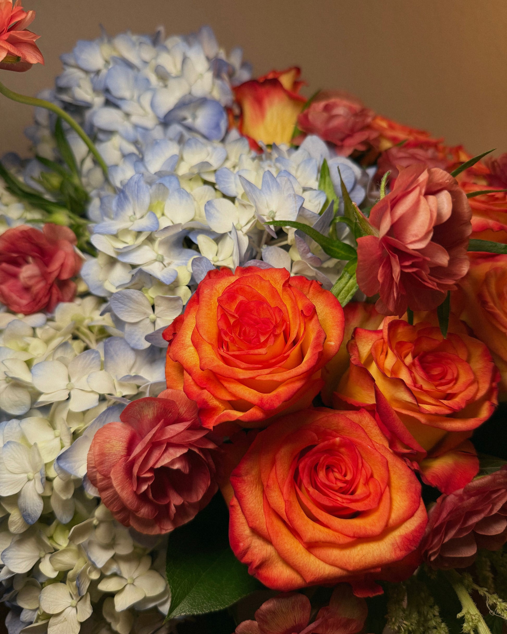 A deluxe bouquet of flowers, including roses and hydrangeas, thoughtfully arranged in a vase by Superbloom floral.