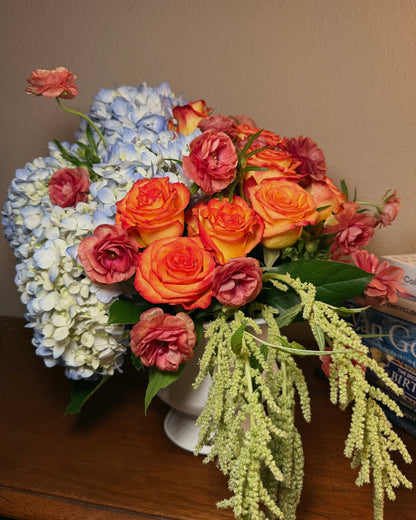 A deluxe bouquet of flowers, including roses and hydrangeas, thoughtfully arranged in a vase by Superbloom floral.