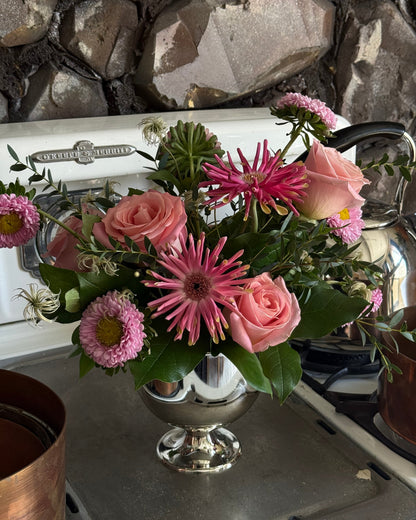 blush roses, spider gerbers, asters, and greens arranged in a vase.