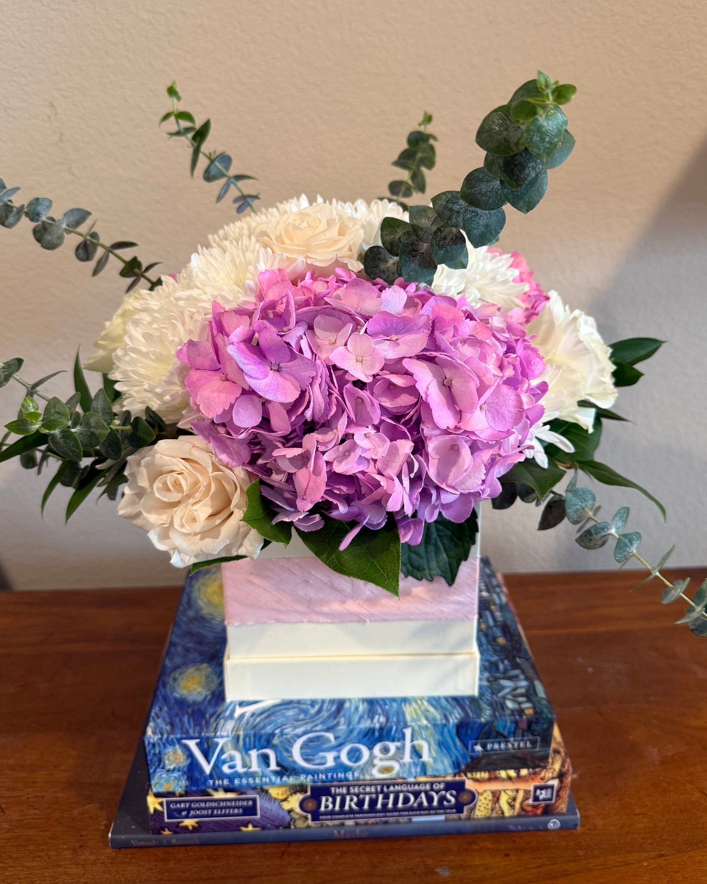Mix of hydrangea, mums, ecuadorian roses, and greens arranged in a small box. 
