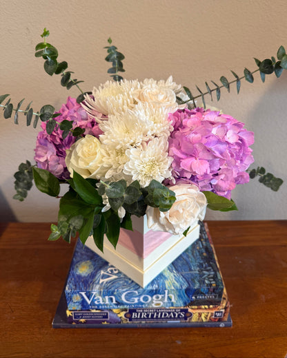 Mix of hydrangea, mums, ecuadorian roses, and greens arranged in a small box. 