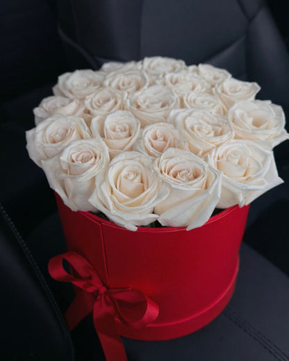 Bouquet of white roses in a red box on a car seat