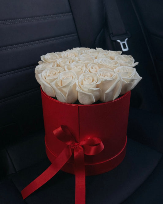 Bouquet of white roses in a red box on a car seat