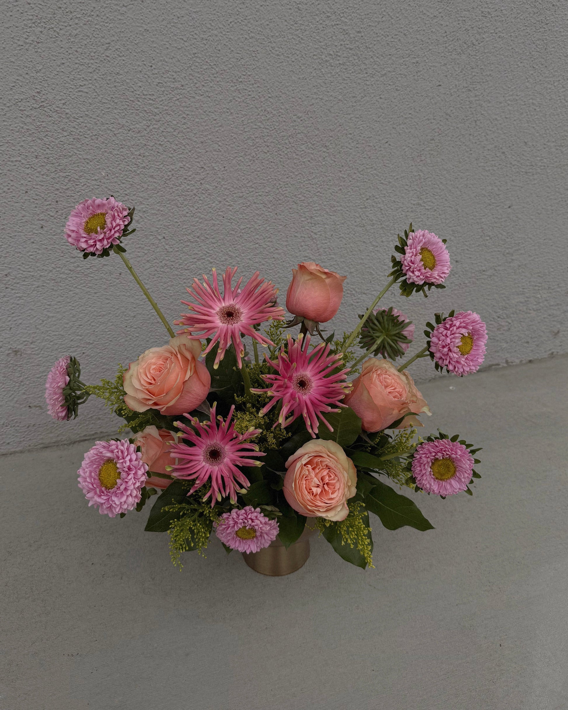 Bouquet of pink and peach flowers in a gold vase.