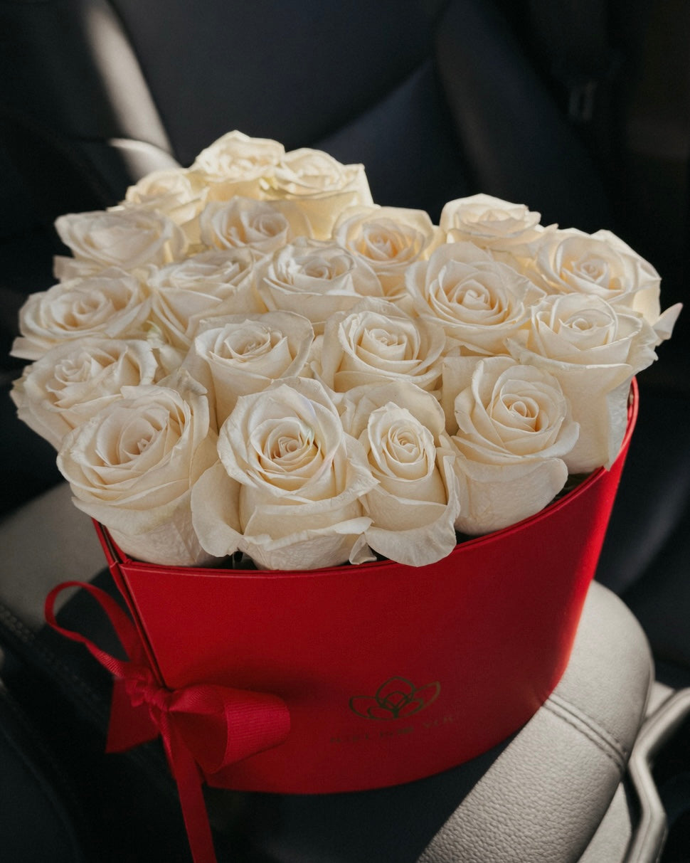 Bouquet of white roses in a red box on a car seat