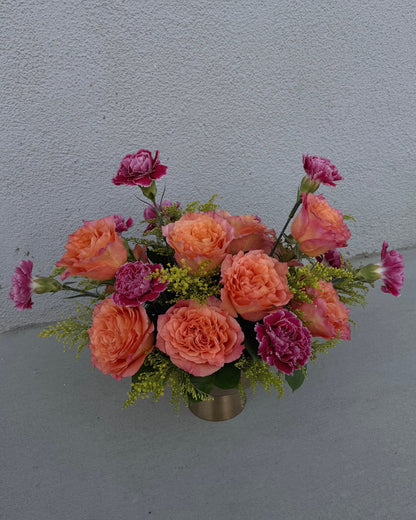 Arrangement of pink carnations and orange garden roses with yellow solidago  in a gold vase