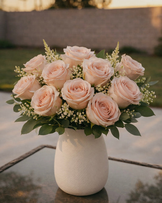 Bouquet of light pink roses in a white vase on a reflective surface with a blurred background