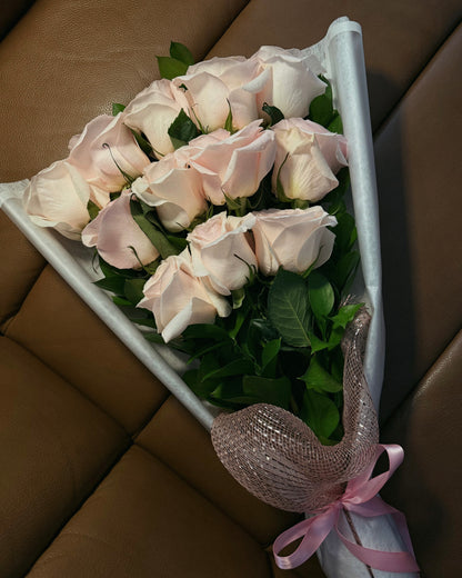 Bouquet of pink roses with greenery against a brown leather background.