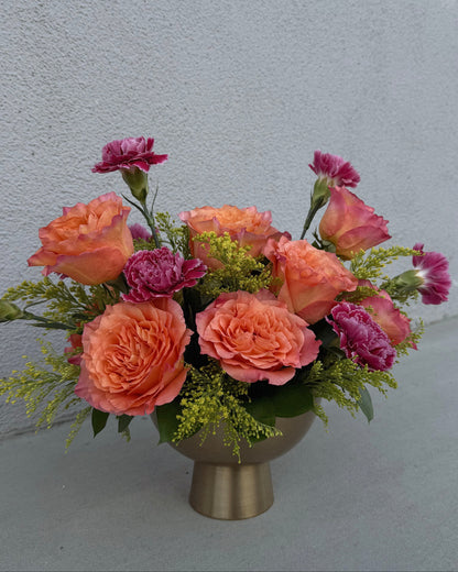Arrangement of pink carnations and orange garden roses with yellow solidago  in a gold vase