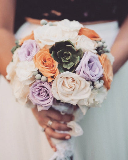 Bouquet of flowers with roses and succulents held by a person.